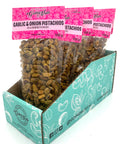 5 clear bags of spiced pistachios with pink labels on top.