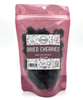 A pink bag with a clear front is filled with dark red dried cherries with a white and pink label on the front 
