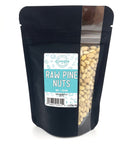 A black zippered bag filled with pine nuts with a window on the right side and a teal and white label on the front
