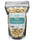A black zippered bag filled with raw cashews with a clear front and a teal and white label on the front