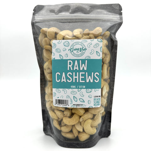 A black zippered bag filled with raw cashews with a clear front and a teal and white label on the front