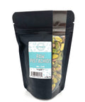 A black zippered bag filled with pistachios with a window on the right side and a teal and white label on the front
