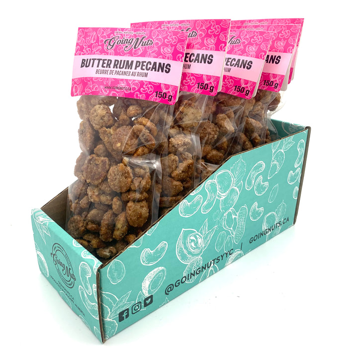 5 bags of candied pecans in clear bags with pink labels on top.