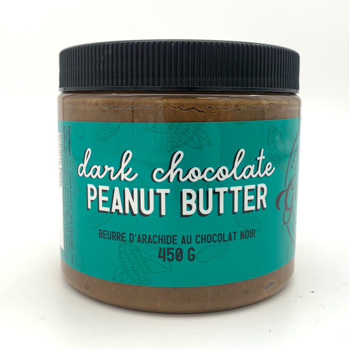 A jar of dark peanut butter with a dark turquoise label which has a cocoa and peanut motif.