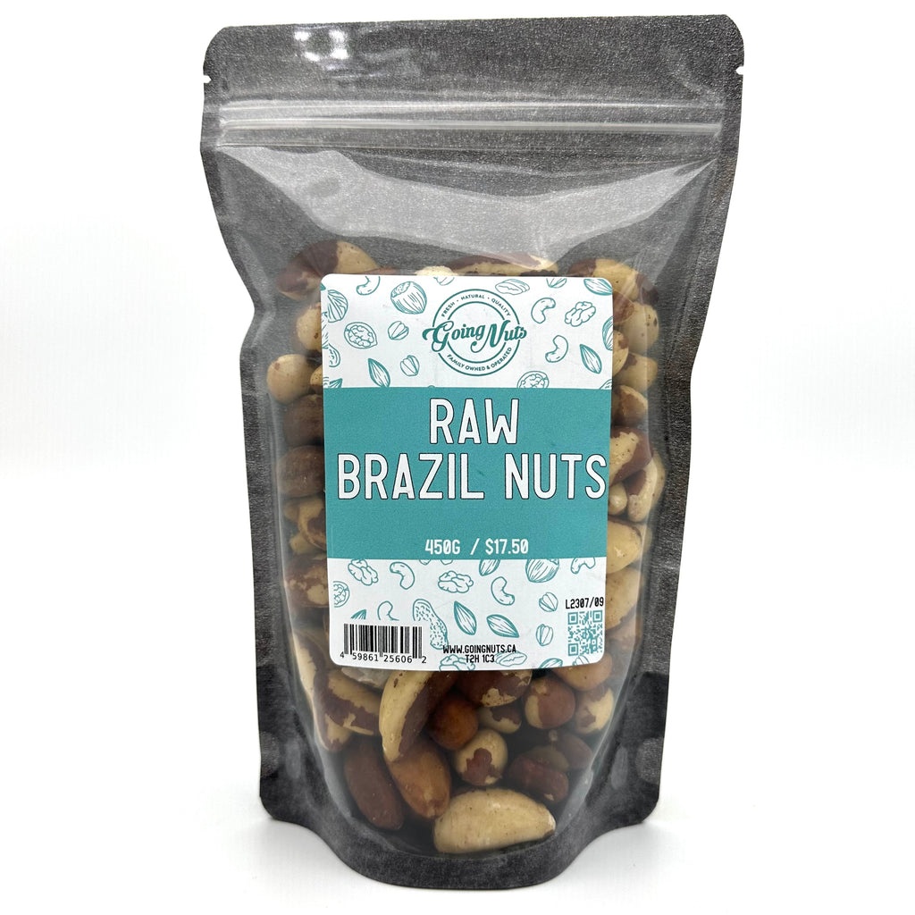 A black zippered bag filled with raw brazil nuts with a clear front and a teal and white label on the front